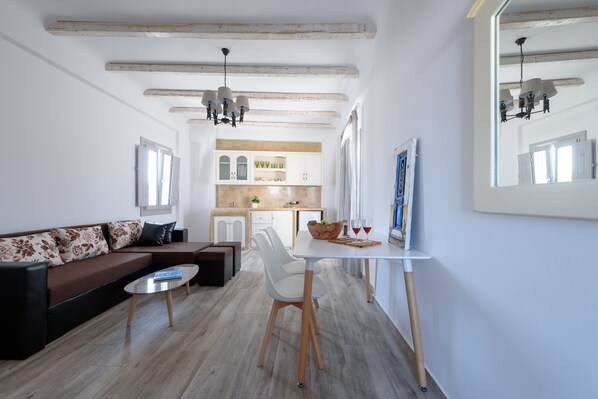Un salon moderne avec un canapé, une table à manger et un coin cuisine à l’arrière-plan.