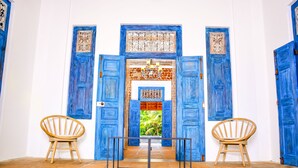 Une pièce avec deux chaises en bois, une table en métal et des portes bleues ornées de motifs complexes.