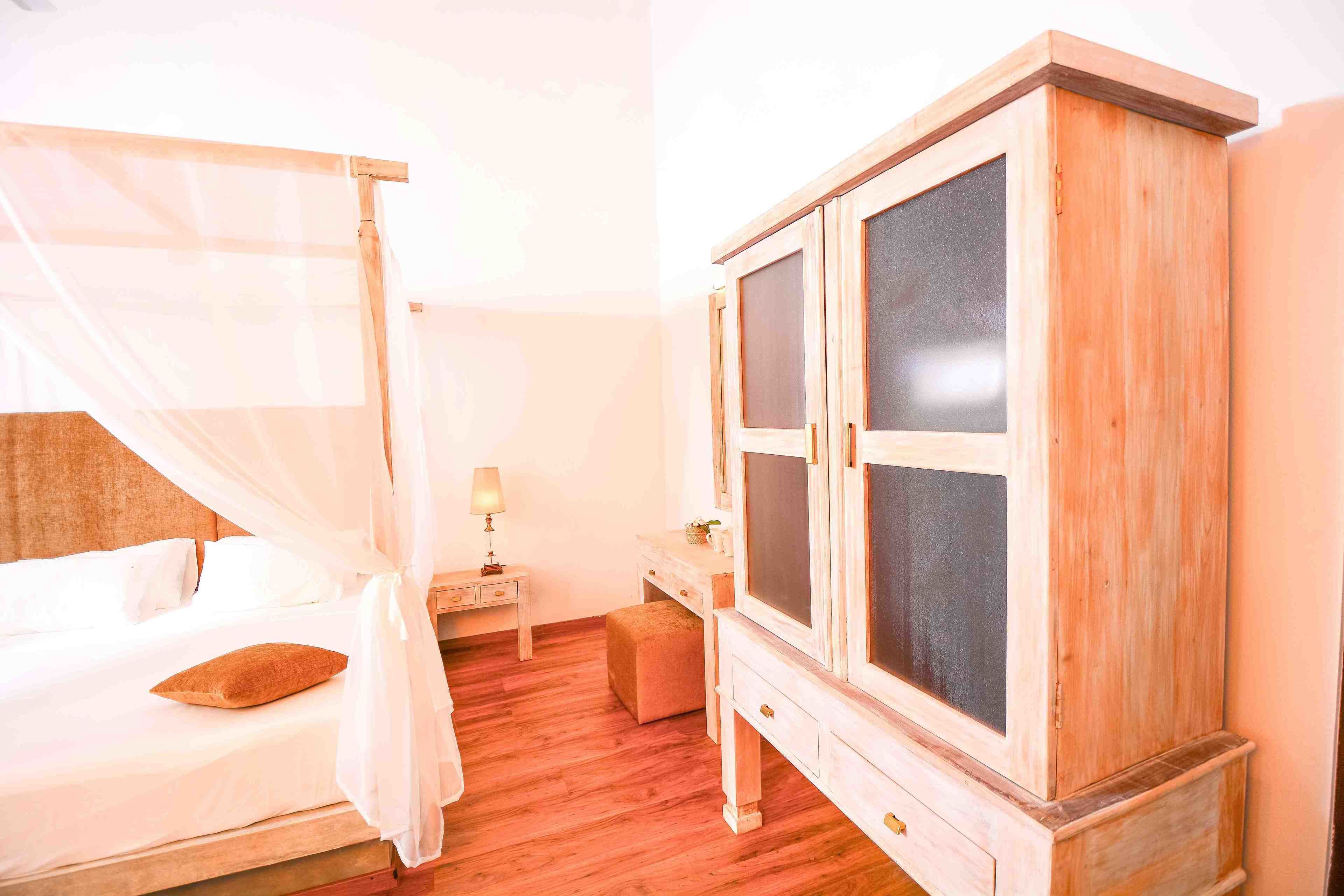 A bedroom with a bed, a wooden wardrobe, a nightstand, and a bedside table.