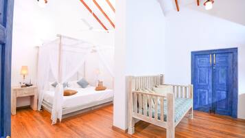 A bedroom with a canopy bed, a wooden desk, and a blue door.