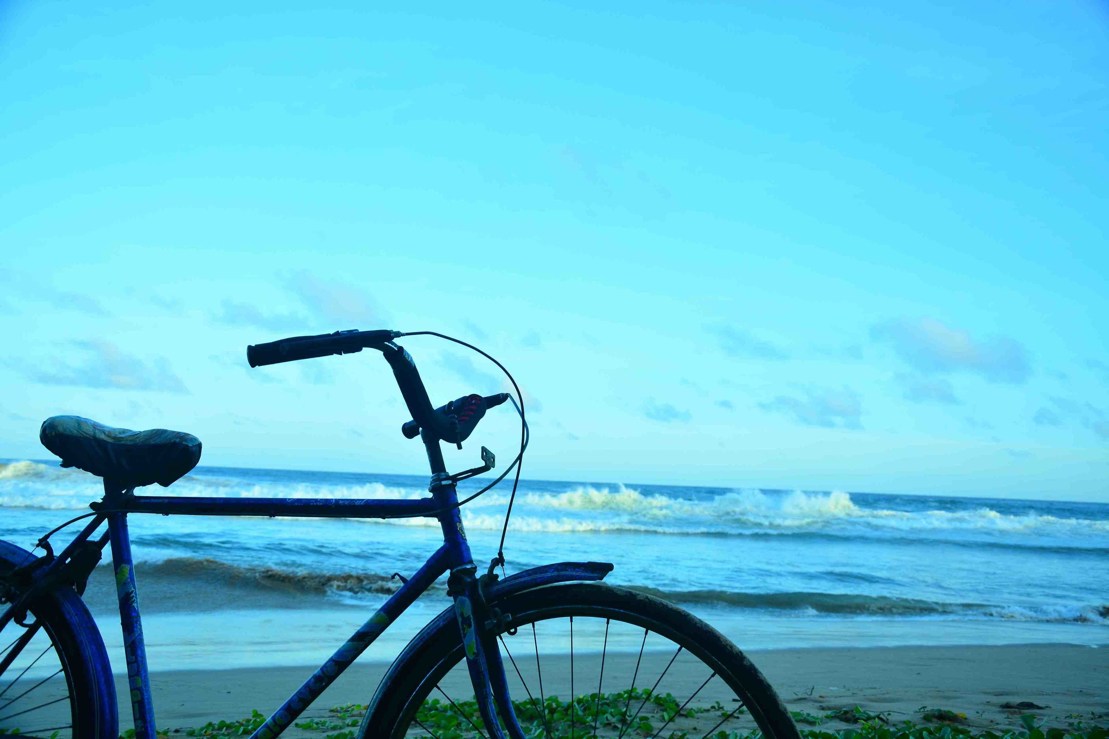 Un vélo garé sur une plage, avec l’océan en arrière-plan.