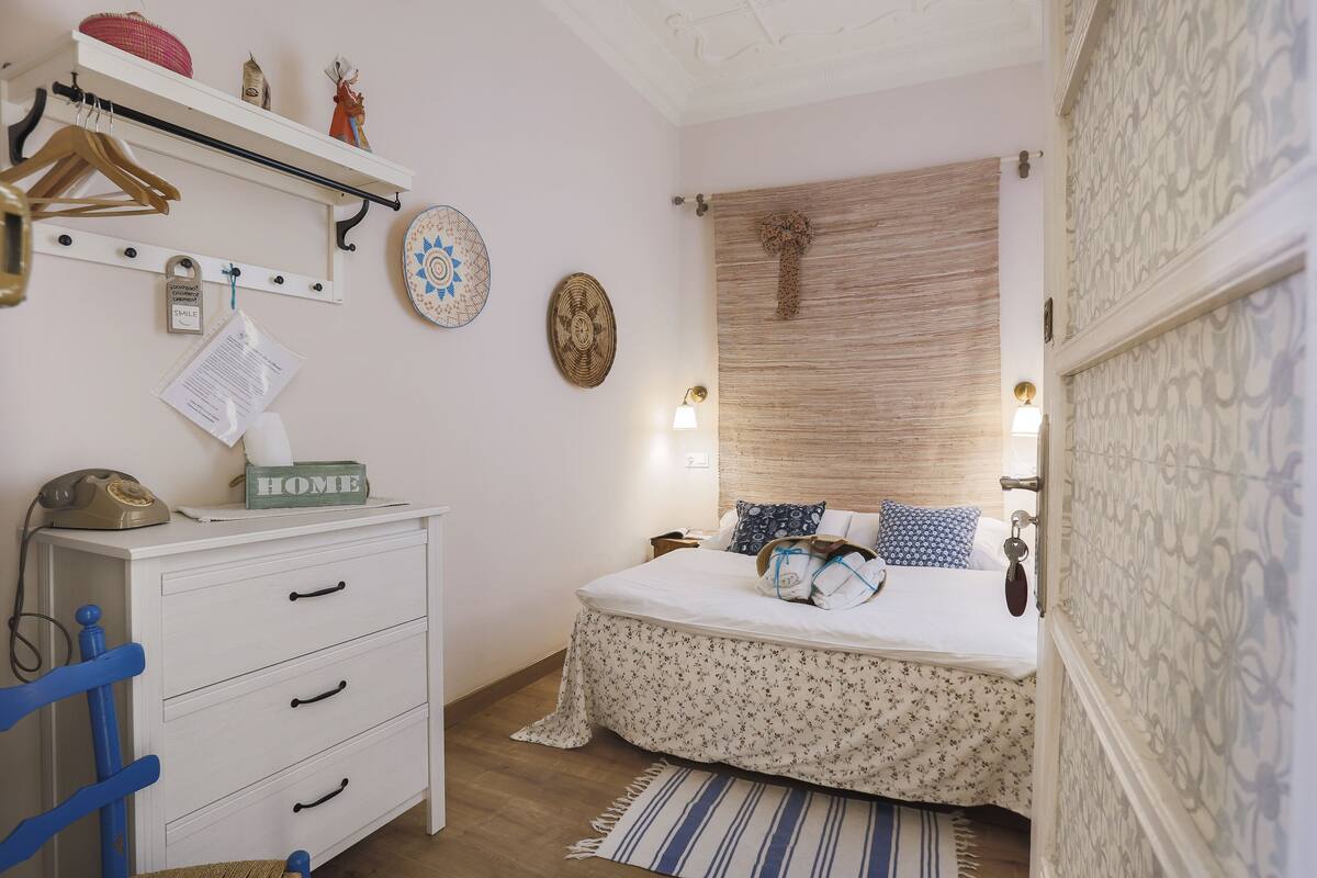 Un dormitorio con cama, cómoda, silla y adornos en la pared.