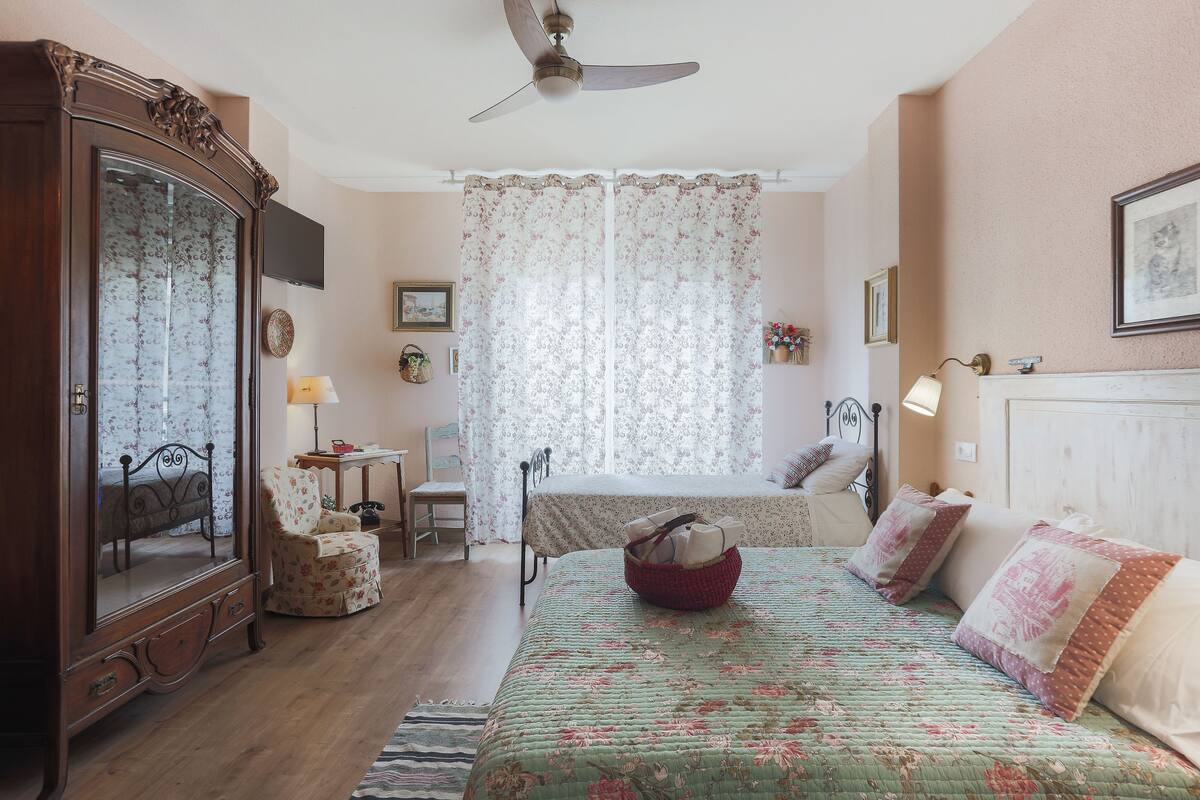 Un dormitorio con cama, cómoda, silla, escritorio y ventilador de techo.