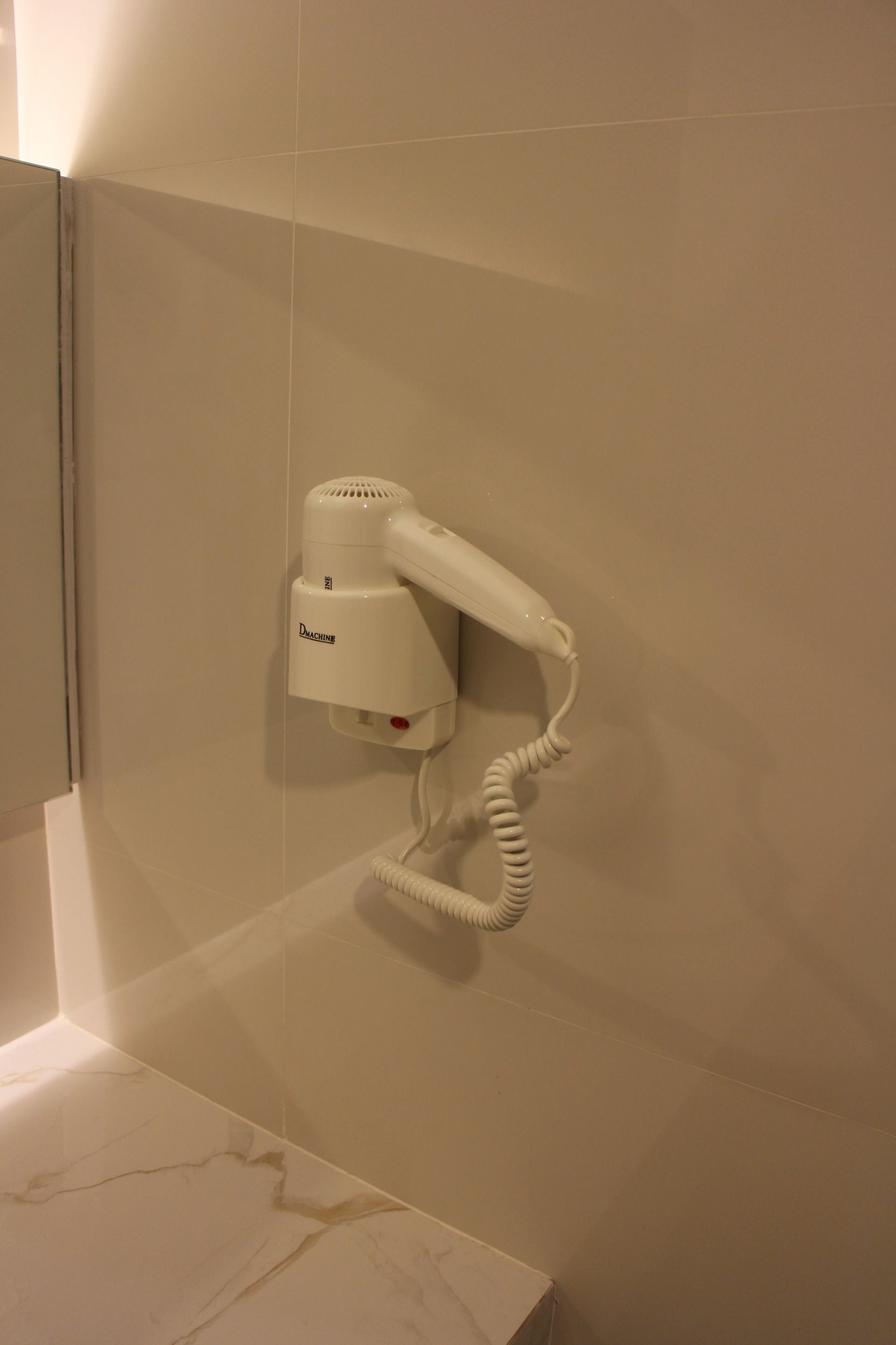 A hair dryer mounted on a wall in a bathroom.