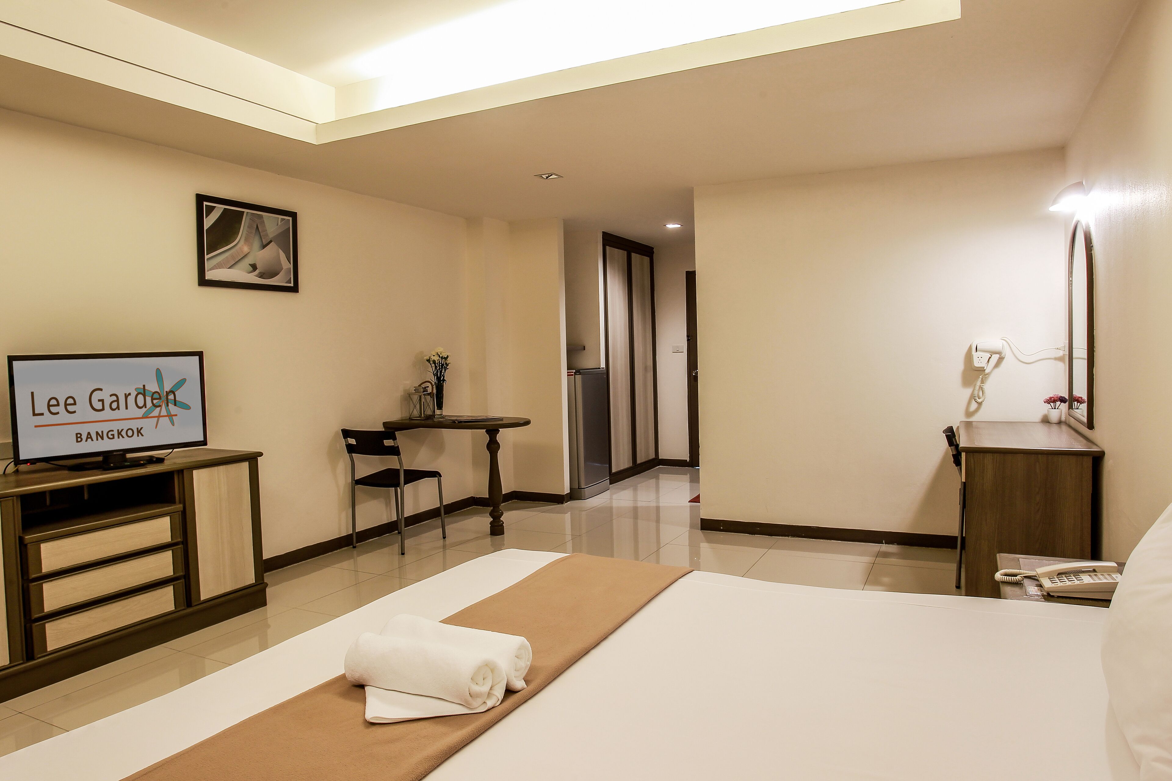 A hotel room with a bed, a TV, a desk, and a chair.