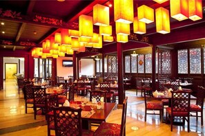 A restaurant with wooden tables and chairs, hanging lanterns, and traditional Chinese window designs.