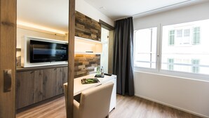 Una cocina moderna con microondas integrado, armarios de madera y un comedor con una silla blanca.