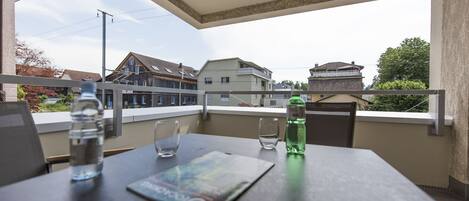 A balcony with a table, two glasses, and two water bottles.