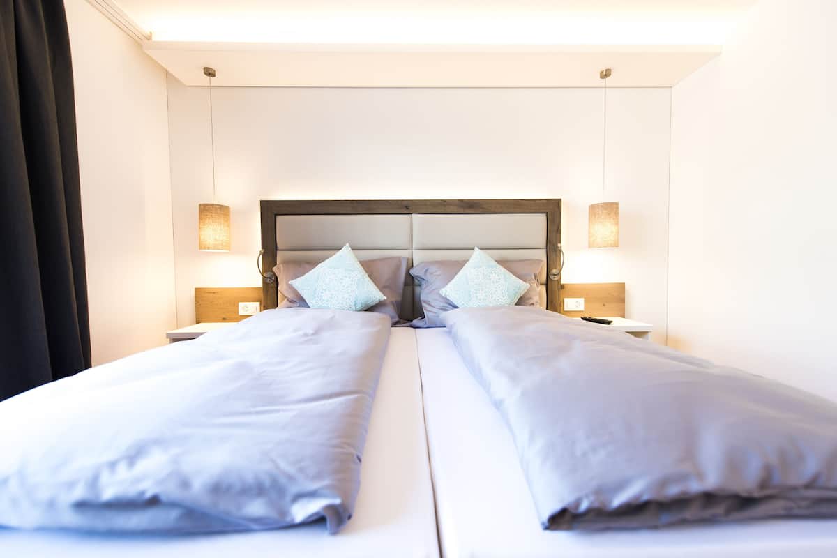 A hotel room with a large bed, two bedside tables, and a headboard with a mirror.