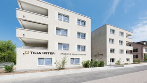 Un edificio moderno de Tilia Uster con varios balcones, identificado como motel y apartamentos.