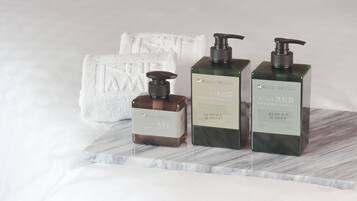 Three bottles of F&G hand soap and shampoo on a marble surface with a white towel in the background.