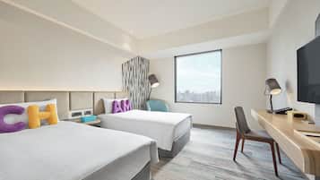 A hotel room with two beds, a desk, a chair, and a large window.