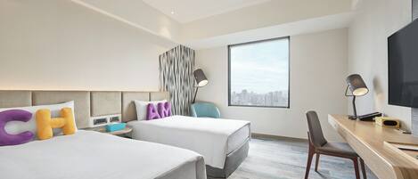 Una habitación de hotel con dos camas, un escritorio, una silla y un ventanal grande.
