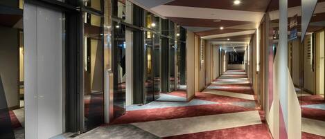 A corridor with glass doors, a patterned carpet, and a ceiling with recessed lighting.