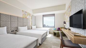 A hotel room with two beds, a desk with a chair, a TV, and a window with a city view.
