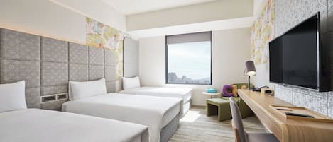 A hotel room with two beds, a desk with a chair, a TV, and a window with a city view.