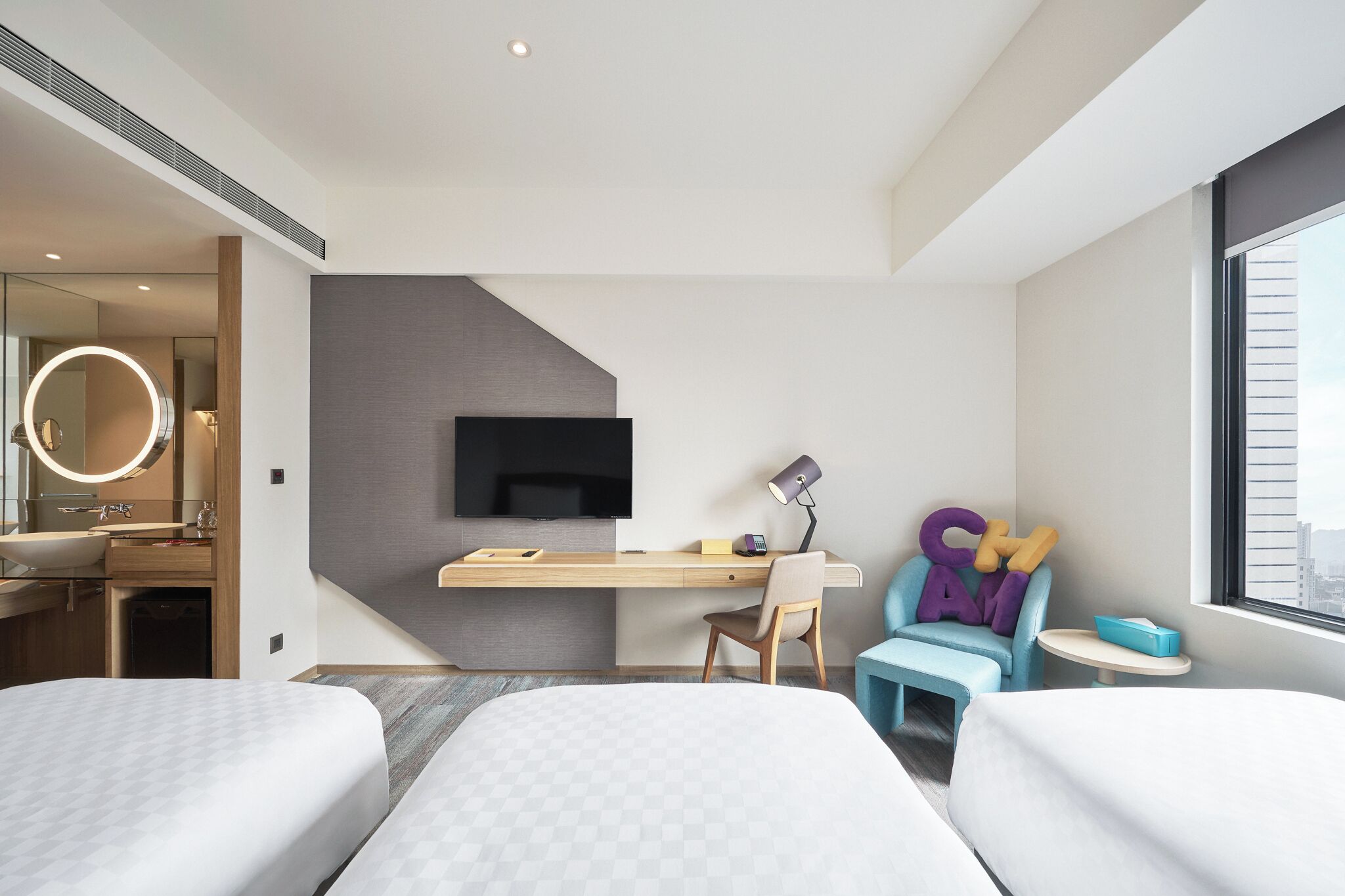 Una habitación de hotel moderna con cama, escritorio, silla, televisor y ventana.