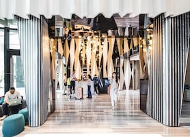 Un área de registro de hotel moderna con un diseño contemporáneo, que presenta patrones geométricos y un mostrador de recepción central.