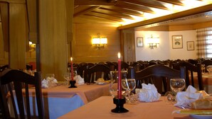 A dining area with tables set for a meal, candles, and wall-mounted lighting. - Sport Hotel Pampeago (Tesero)