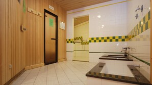 A bathroom with a wooden door, a sink with a mirror, and a checkered tile border. - Sport Hotel Pampeago (Tesero)