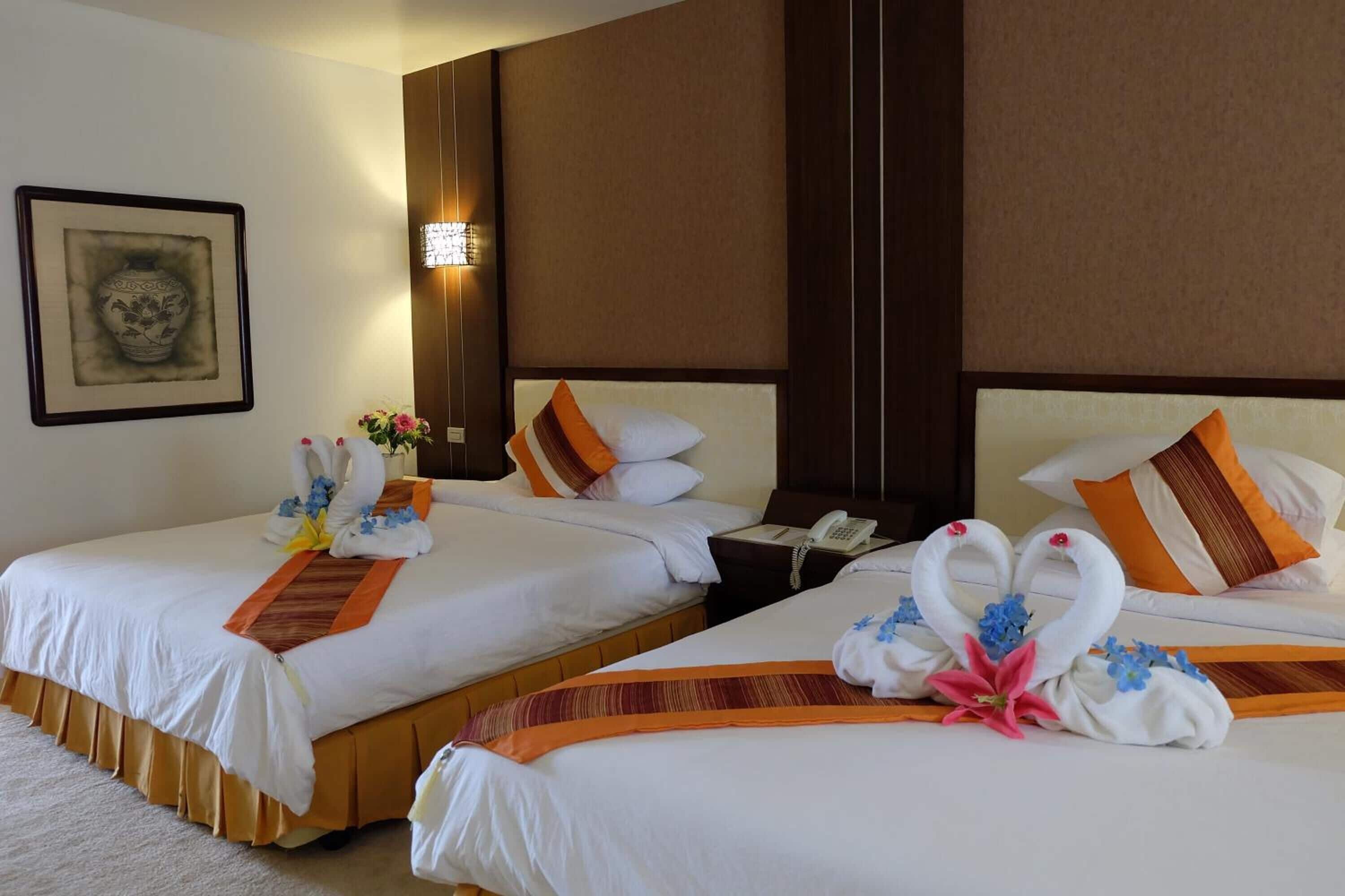 A hotel room with two beds, each adorned with decorative swans and flowers.