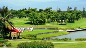 Um campo de golfe com lago, árvores e um pavilhão.