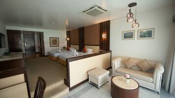 Una habitación de hotel con cama, sofá, mesa de centro y televisor.