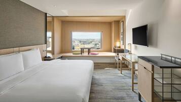Een moderne hotelkamer met een groot bed, een bureau, een televisie en uitzicht op de stad.
