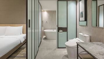 Una camera d'albergo moderna con un letto, un bagno con vasca, water e lavandino.