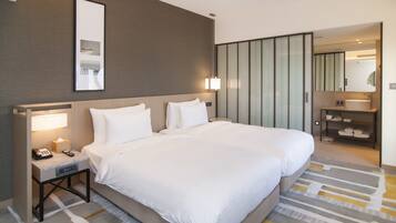 A hotel room with a large bed, bedside tables with lamps, a mirror, and a bathroom with a sink and shelves.