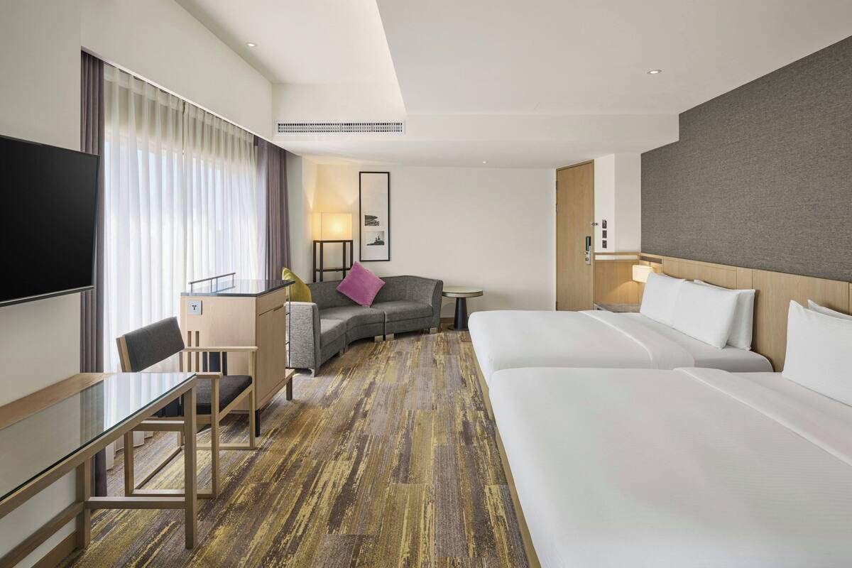 A hotel room with a large bed, a desk, a sofa, and a TV.