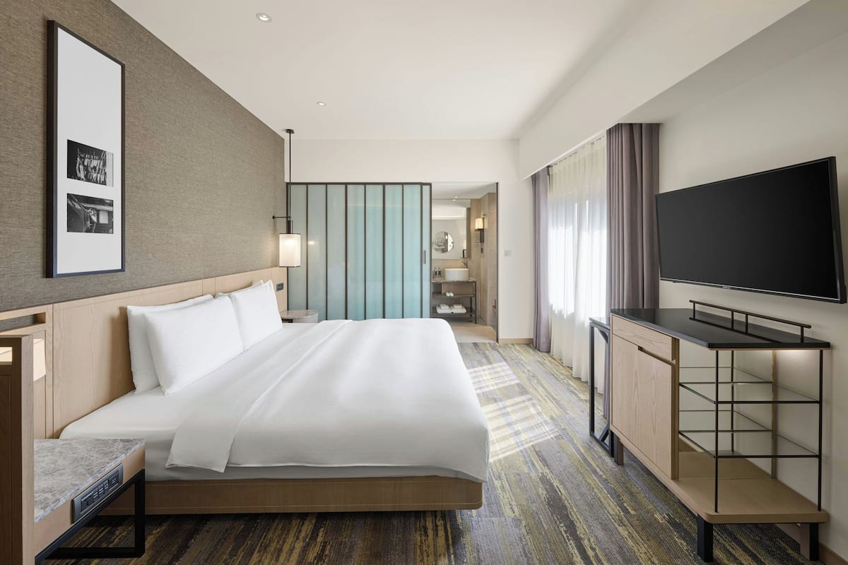 A hotel room with a large bed, a TV, a desk, and a wardrobe.