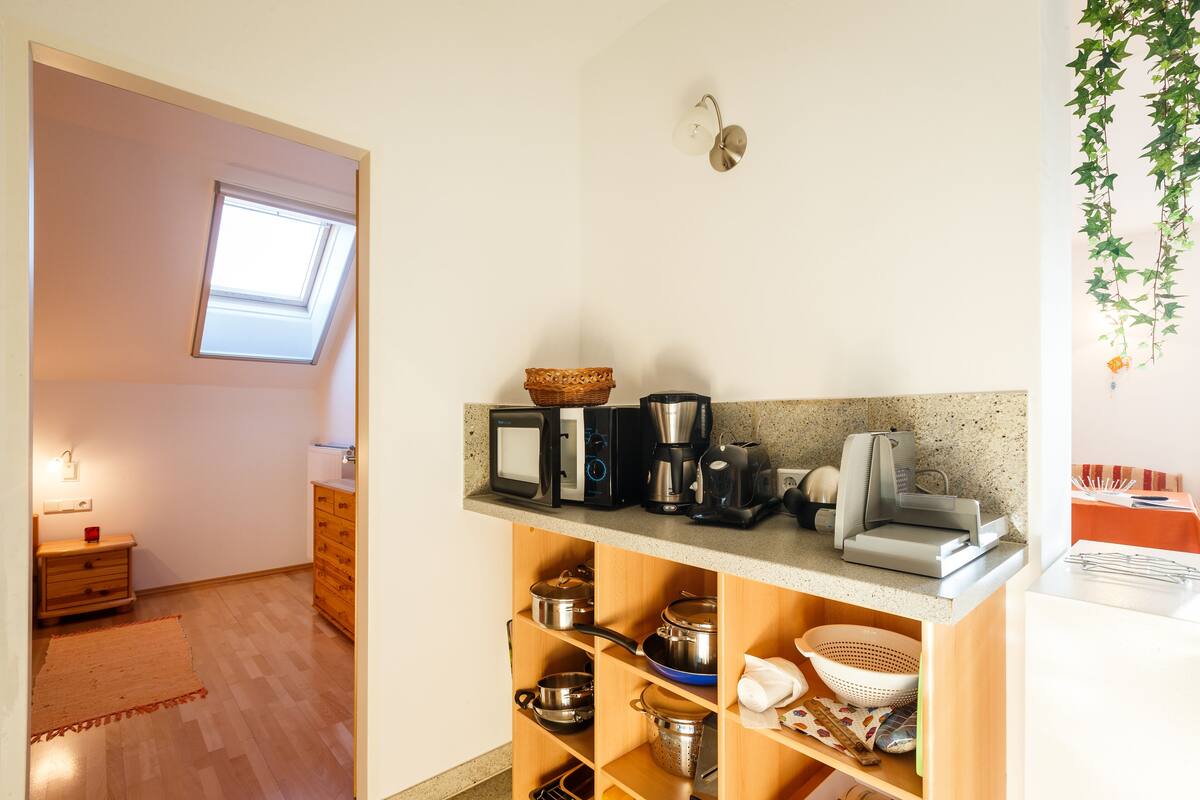 A compact kitchen with a microwave, coffee maker, and various pots and pans on shelves.