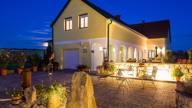 A two-story house with a balcony, potted plants, and outdoor seating. - Appartmenthaus Freiler (Morbisch am See)