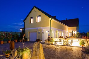 A two-story house with a balcony, potted plants, and outdoor seating. - Appartmenthaus Freiler (Morbisch am See)
