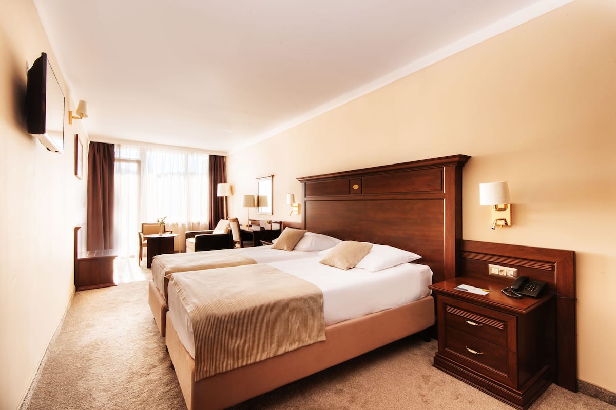 A hotel room with two beds, a desk, a chair, and a TV mounted on the wall.