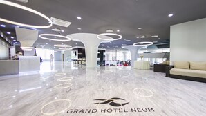 Un moderno vestíbulo de hotel con piso de mármol, luces circulares en el techo y un mostrador de recepción.