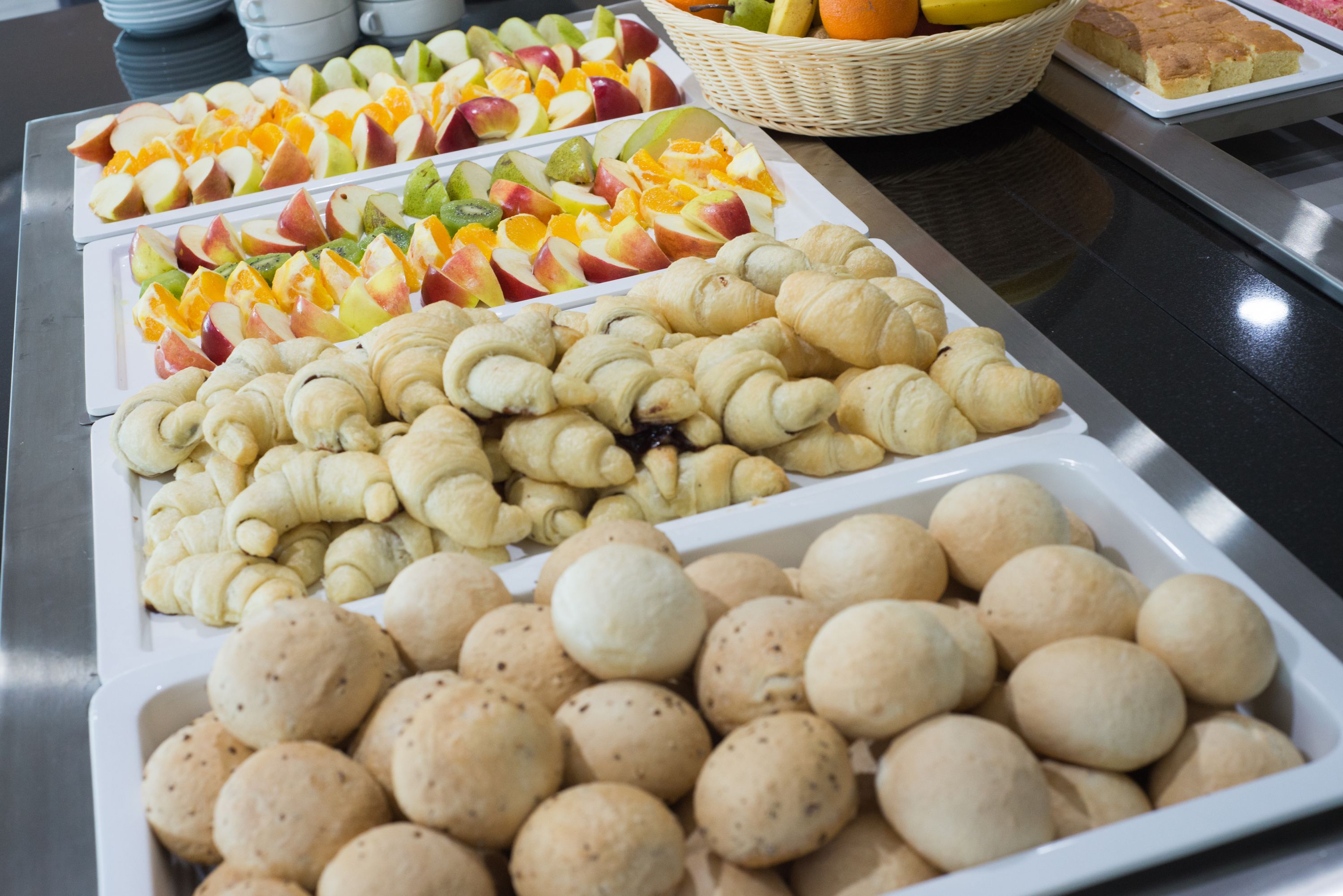 Un bufé con diversas opciones de comida, incluyendo frutas, pasteles y pan.