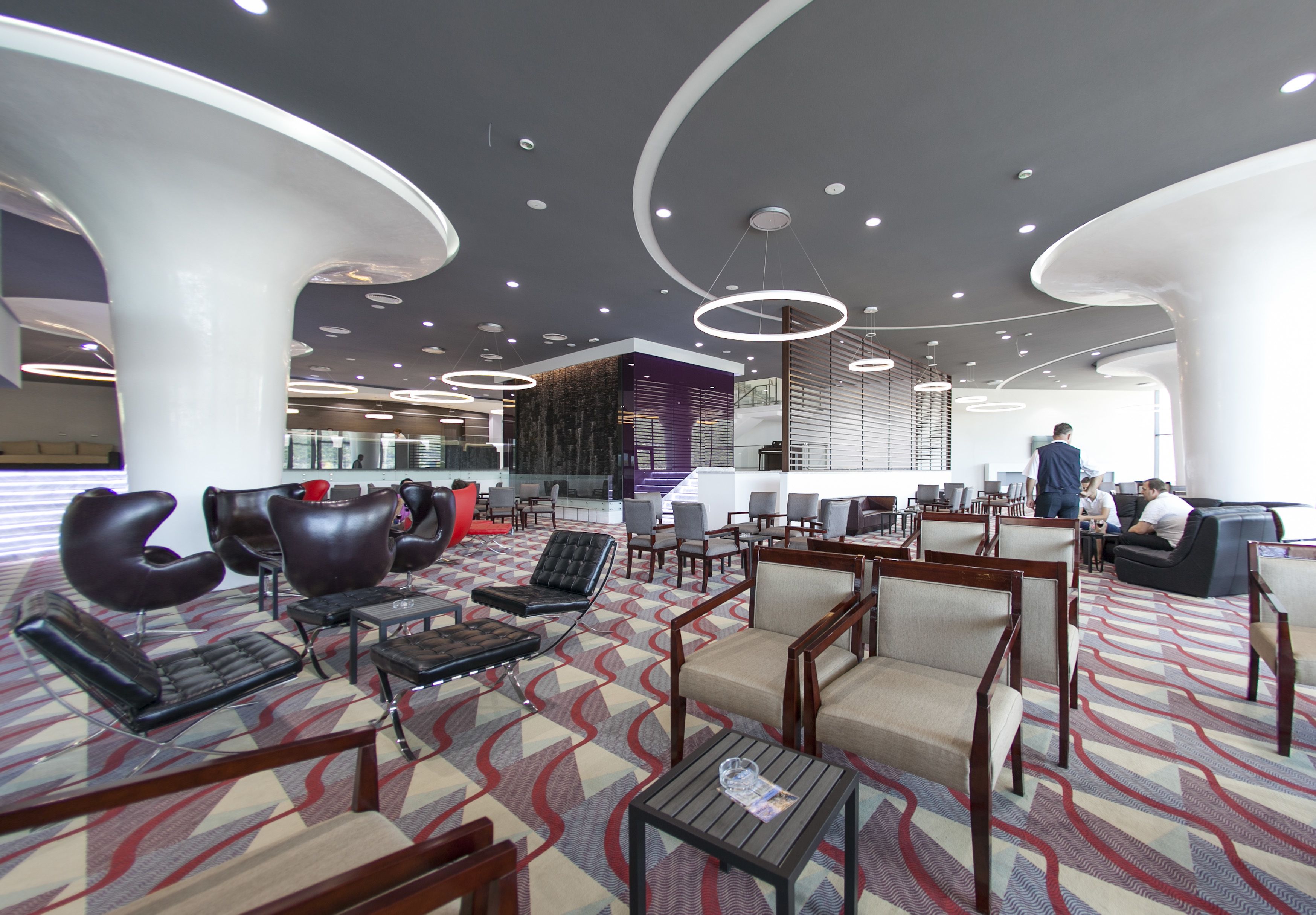 A modern lobby with seating areas, a reception desk, and a patterned carpet.
