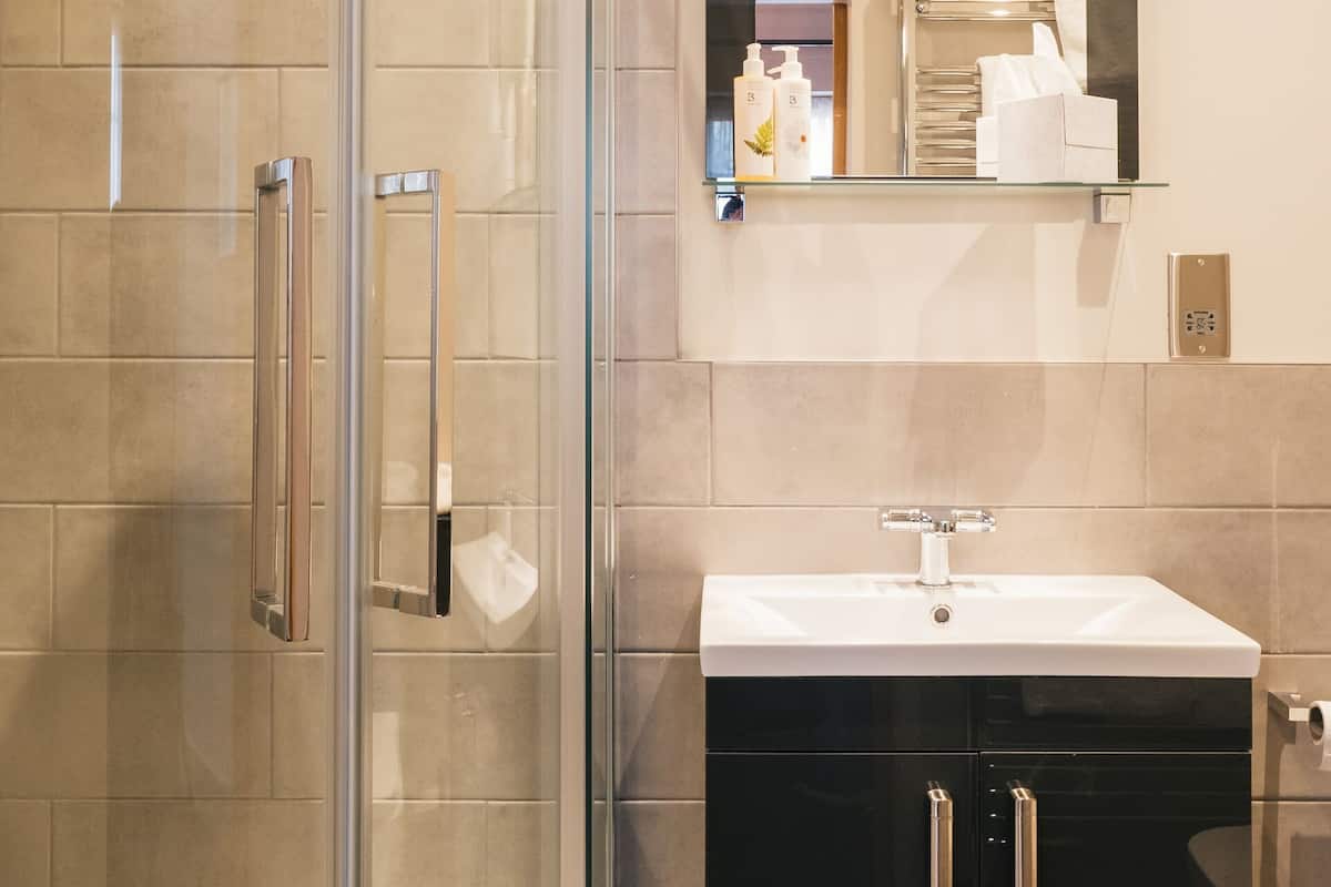 A modern bathroom with a glass-enclosed shower, a white sink, and a black cabinet.