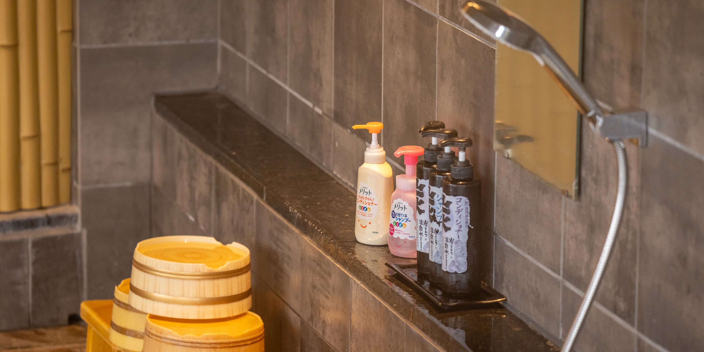 A bathroom with a shower, a shelf with toiletries, and wooden containers.