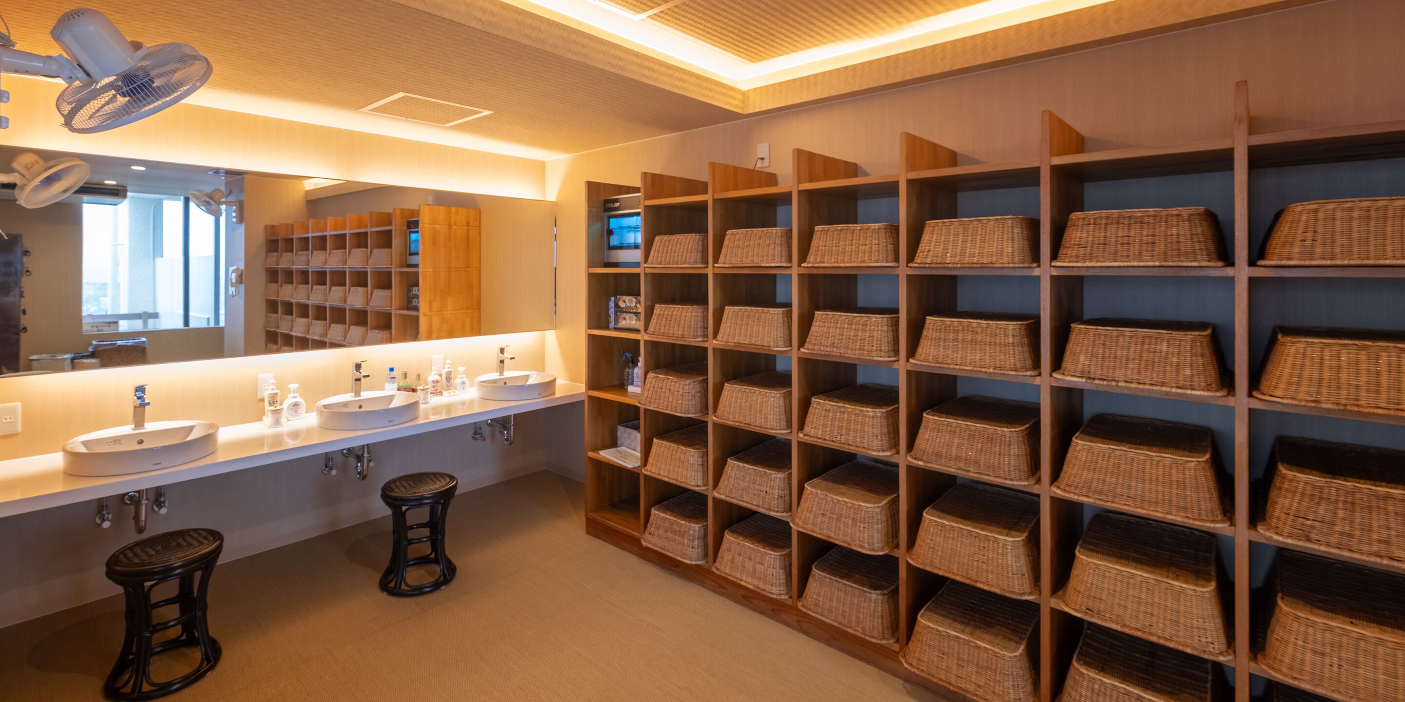 A modern bathroom with two sinks, a large mirror, and shelves with wicker baskets.