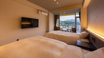 Habitació d'hotel amb dos llits, una televisió penjada a la paret, un balcó amb vista a la ciutat i un disseny modern.
