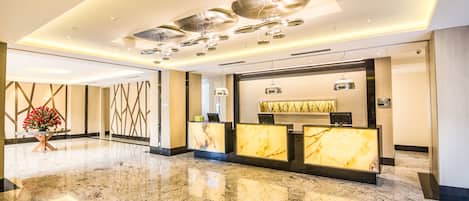 A modern hotel lobby with marble flooring, a reception desk, and contemporary lighting fixtures.