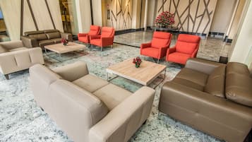 A lobby with beige and red sofas, a coffee table, and a decorative wall.