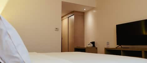 Une chambre d’hôtel équipée d’un lit, d’une télévision, d’une machine à café et d’une armoire.