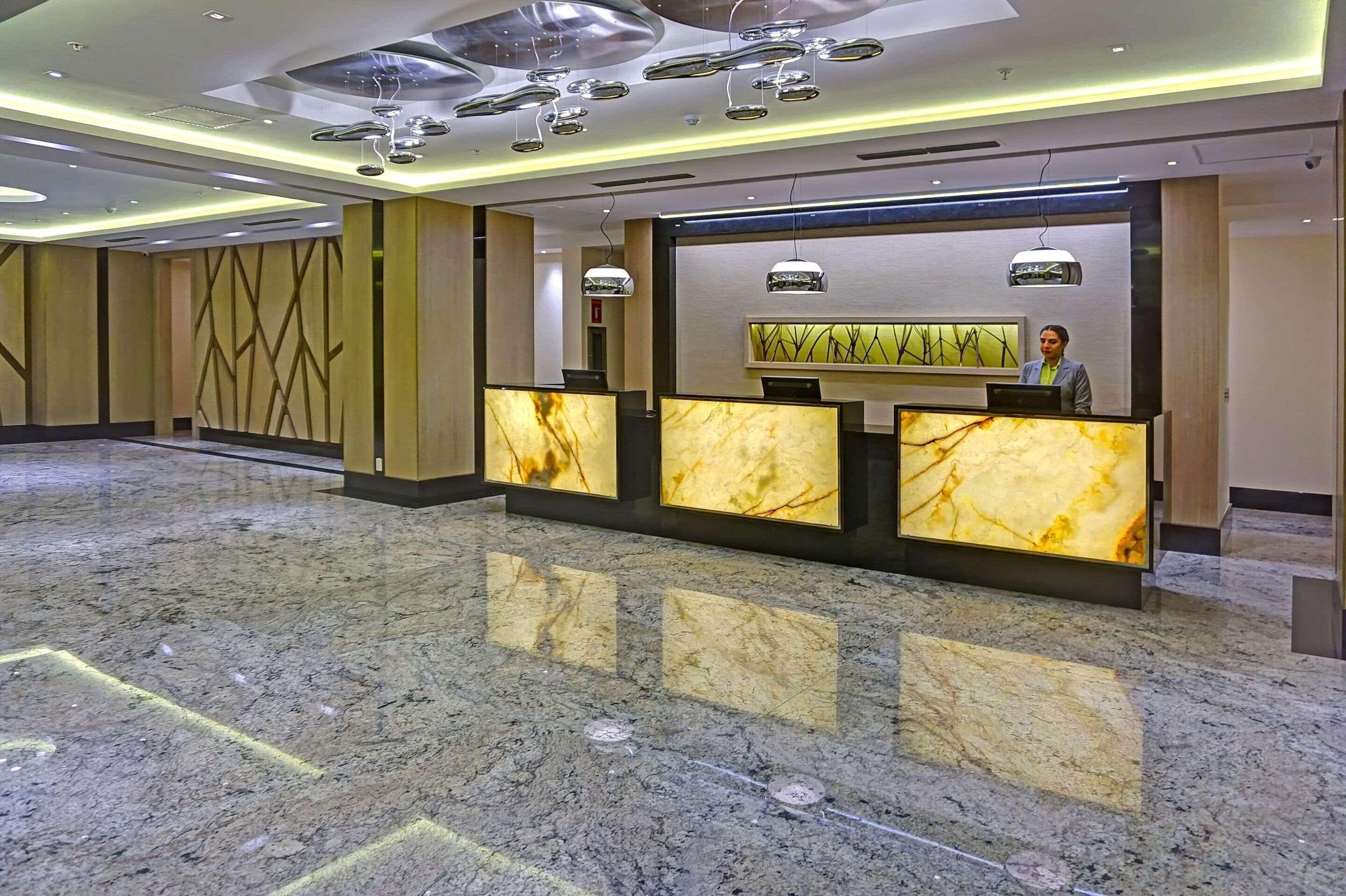 Zona d'adreça d'hotel amb taulells de marbre, il·luminació moderna i un sòl net i polit.