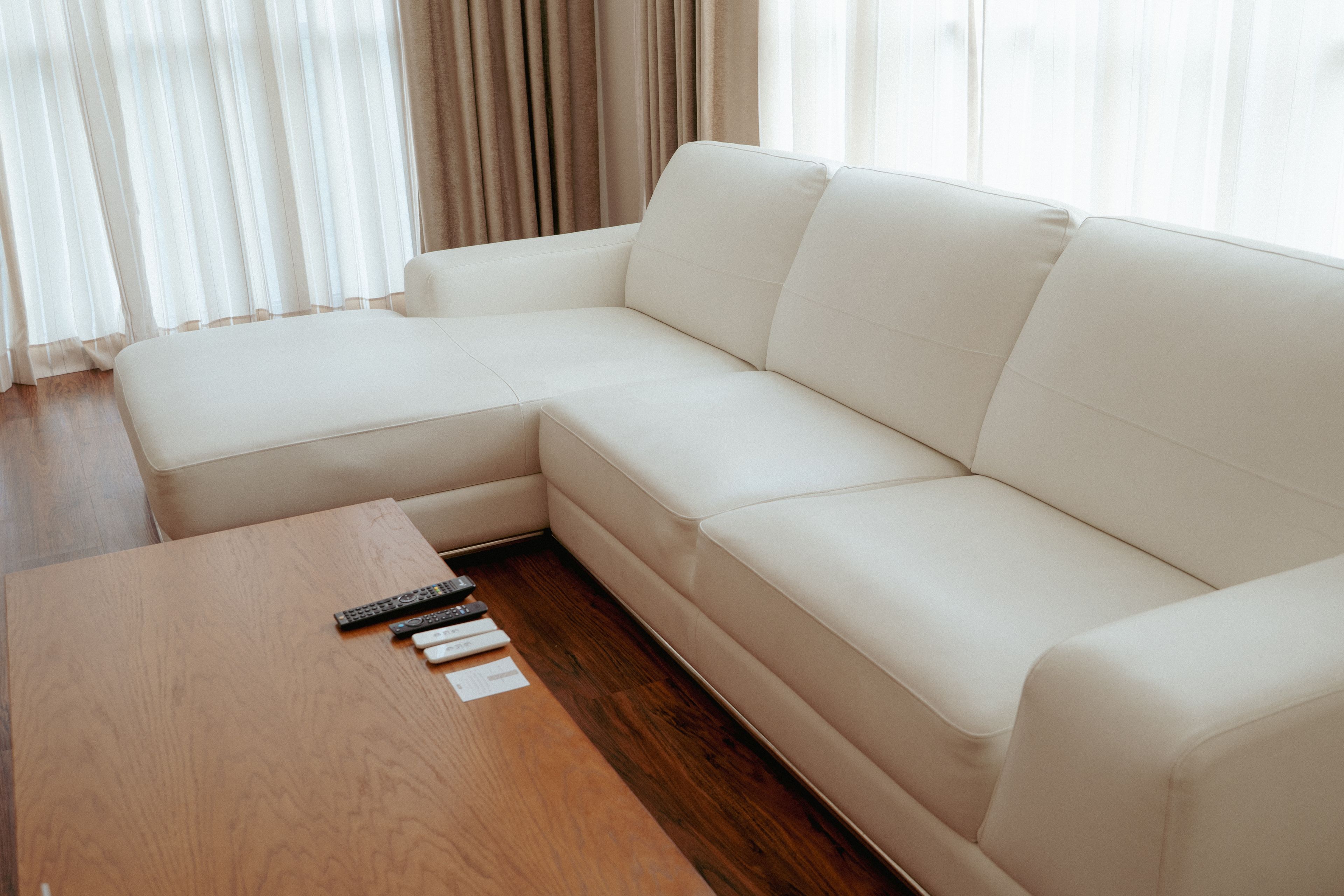A modern living room with a sectional sofa, a wooden coffee table, and a remote control.