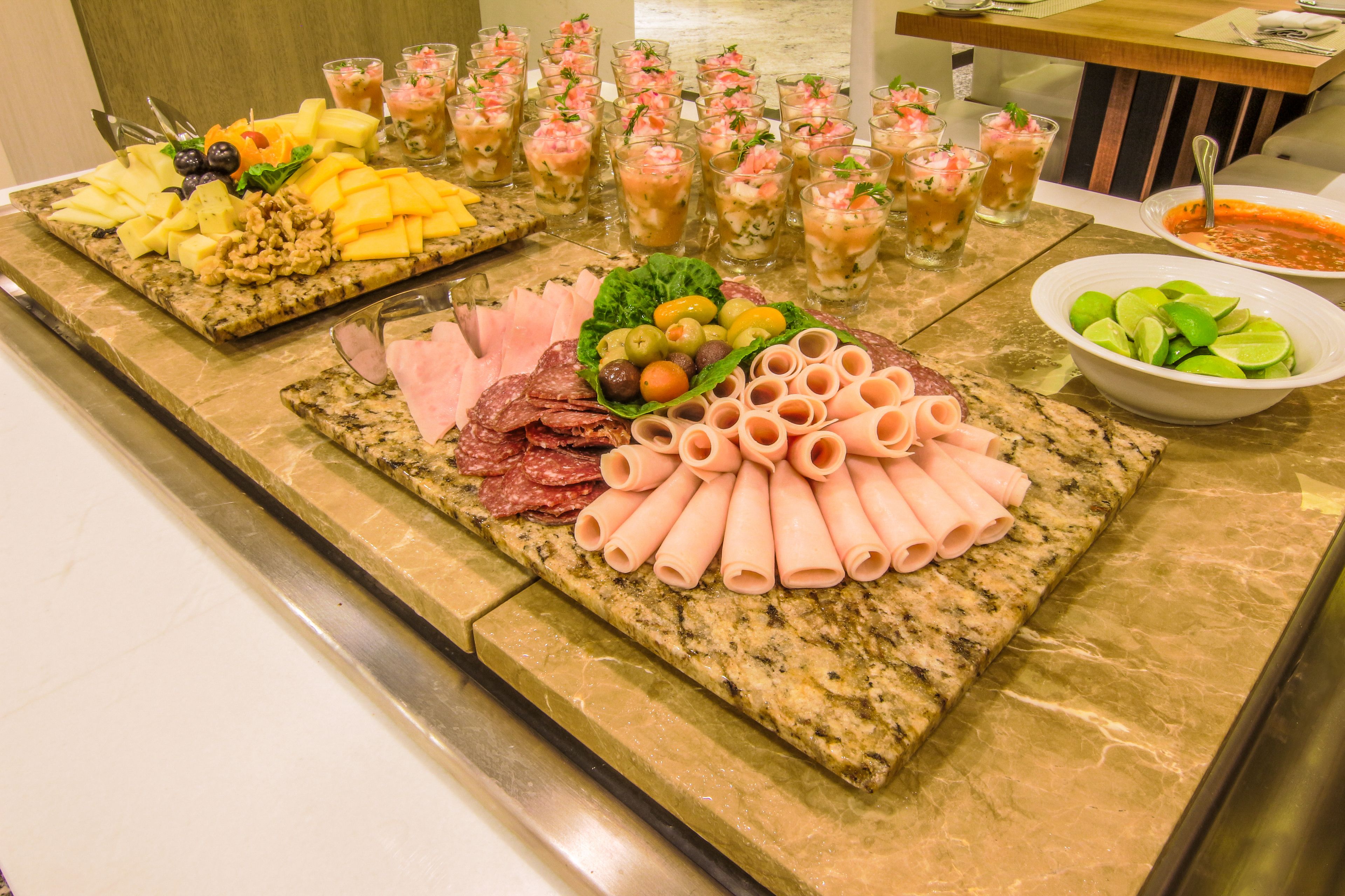 Een buffet met diverse etenswaren, waaronder kazen, vlees en een schaal met partjes limoen.