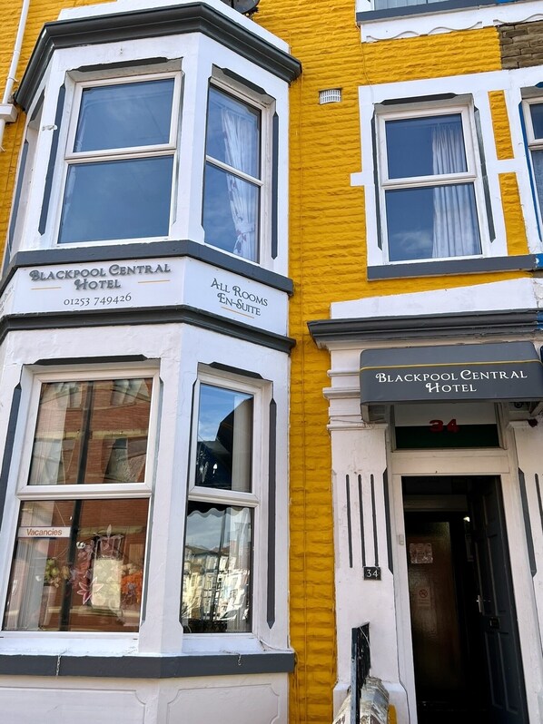 Un edificio en esquina con un cartel que indica Blackpool Central Hotel, indicando que todas las habitaciones tienen baño privado.